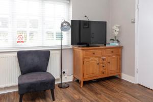 a living room with a chair and a television on a dresser at The Gillett's Cottage in Wantage