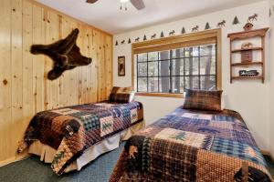 two beds in a room with wooden walls and a window at Retreat to Fox Farm-1662 by Big Bear Vacations in Big Bear Lake