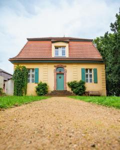 ein gelbes Haus mit blauer Tür auf einer unbefestigten Straße in der Unterkunft Kavaliershaus Krumke - Gästehaus im Schlosspark - mit Schlüsselbox, ohne TV in Krumke