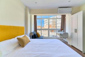 a bedroom with a white bed and a view of a building at Malaguetabeach apartment in Málaga