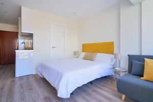 a bedroom with a white bed and a blue couch at Malaguetabeach apartment in Málaga +4 photos