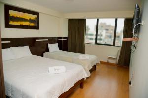 a hotel room with two beds and a window at Hotel San Román ⋆⋆⋆ in Juliaca