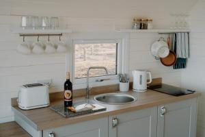 a kitchen counter with a sink and a bottle of wine at Strathy Bay Pods in Strathy