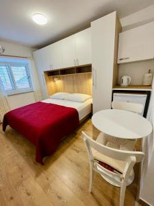 a bedroom with a bed with a red blanket and a table at Guest House Korunić in Korčula