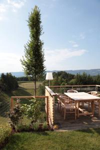 a wooden deck with a table and chairs on it at Hof Niglberg Südsteiermark in Sankt Johann im Saggautal