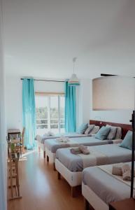 fila de camas en una habitación con cortinas azules en Wellnesshouse, en Atouguia da Baleia