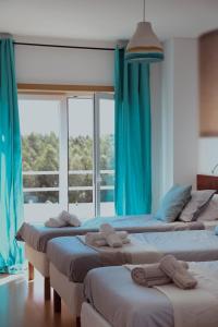 a room with four beds with blue curtains and a window at Wellnesshouse in Atouguia da Baleia