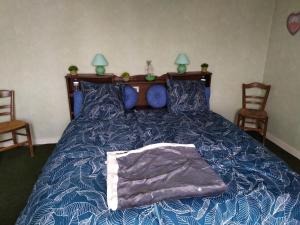 une chambre avec un lit avec une couette bleue et deux chaises dans l'établissement Chambre d hôte de la paix, à La Rochefoucauld