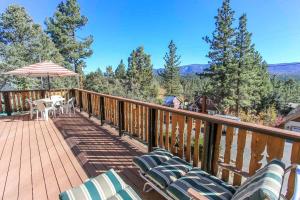 eine Terrasse mit Stühlen, einem Tisch und einem Sonnenschirm in der Unterkunft Above it All-1685 by Big Bear Vacations in Big Bear City