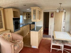 uma cozinha com armários de madeira, uma mesa e uma cadeira em Static Caravan-Field View in lovely countryside OPEN MARCH-OCTOBER em Stratford-upon-Avon
