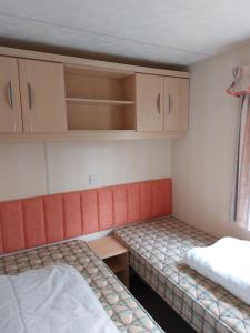 a small room with two beds and wooden cabinets at Static Caravan-Field View in lovely countryside OPEN MARCH-OCTOBER in Stratford-upon-Avon