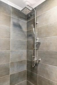 um chuveiro na casa de banho com uma parede de azulejos em Casa Blanca Apartman em Balatonfenyves