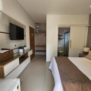a bedroom with a bed and a flat screen tv at Rei dos Mares Suítes in Ubatuba