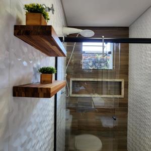a bathroom with wooden shelves and a shower at Rei dos Mares Suítes in Ubatuba