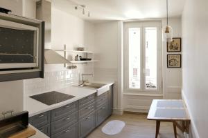 cocina blanca con fregadero y microondas en Le Cheylard, appartement spacieux et lumineux, en Le Cheylard