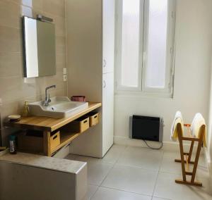 ein Bad mit einem Waschbecken, einem Spiegel und einem Fenster in der Unterkunft Le Cheylard, appartement spacieux et lumineux in Le Cheylard