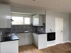 a kitchen with white cabinets and black counter tops at Shore Thing Holiday Chalet Parkdean K81 in Camber