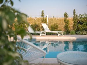 two white chairs sitting next to a swimming pool at Masseria Ella in Pulsano