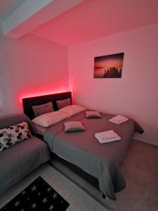 a pink room with two beds and a couch at Studio ELLI KOPER in Koper