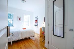 a white bedroom with a bed and a mirror at 4BR 1,5BH Sunny Apt in Roxbury in Boston