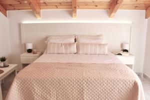 a bedroom with a bed with white walls and wooden ceilings at Comfy Loft at Regina Apartments in Alikanas
