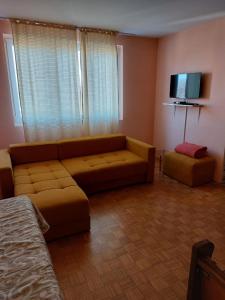 ein Wohnzimmer mit einem Sofa und einem Flachbild-TV in der Unterkunft Apartman UNA in Kruševac