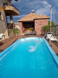uma grande piscina azul com uma casa ao fundo em Casa de Pedra-Vale dos Vinhedos -RS em Monte Belo