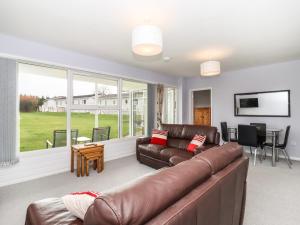 a living room with a leather couch and a table at Marsh Bungalow in Carlton Colville