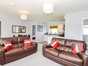a living room with two brown leather couches at Marsh Bungalow in Carlton Colville +13 photos