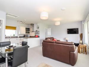 a living room with a couch and a table and a kitchen at Marsh Bungalow in Carlton Colville