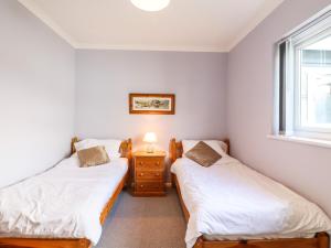 two twin beds in a room with a window at Marsh Bungalow in Carlton Colville