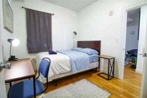 Schlafzimmer mit einem Bett, einem Schreibtisch und einem Stuhl in der Unterkunft 4BR 1,5BH Sunny Apt in Roxbury in Boston