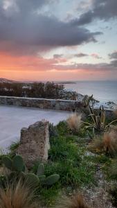 a sunset over the ocean with a stone wall at Arion suites Mykonos in Mikonos