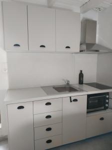 a white kitchen with a sink and a microwave at To Spiti Tou Papa Sto Vouno in Kamilari