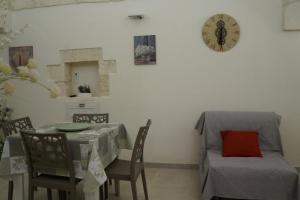 une salle à manger avec une table, des chaises et une horloge dans l'établissement CASETTA SALVATORE, à Ostuni