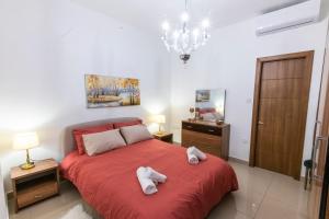 - une chambre avec un lit rouge et des serviettes dans l'établissement Rua Cosy Apartment Sliema (3 Bedroom 2 Bathroom), 2 mins walk from sea, à Sliema