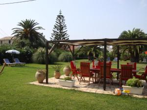 een patio met een tafel en stoelen onder een prieel bij Eleftheria Studios and Apartments in Acharavi