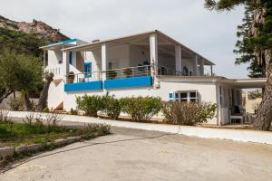 a white house with blue balconies on a street at Villa Giorgos in Kefalos