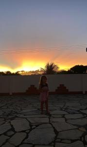 a little girl standing in front of the sunset at A Pousada. in Barra dos Coqueiros