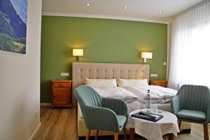 a bedroom with a bed and two chairs and a table at Hotel Eifelstube in Rodder