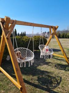two swings in a yard with two dogs laying on them at Apartmani Neven in Irig