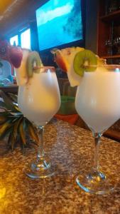 two cocktails sitting on a counter with a tv at Hotel Sumpa in Montañita