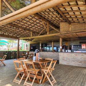 un restaurante con mesa de madera y sillas y un bar en Rei dos Mares Suítes by Easy Hotéis, en Ubatuba