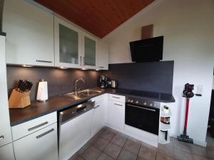 una cucina con mobili bianchi e un piano di lavoro nero di Haus Vier Pfoten - Hundefreundliches Ferienhaus an der Nordsee a Schweiburg