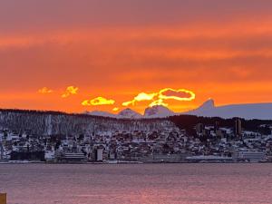 a sunset over a city with mountains in the background at Polar Arctic View - Free Parking! in Tromsø