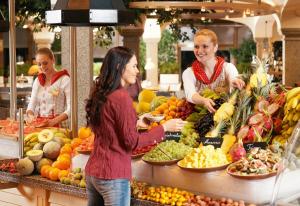 three women standing in a market with fruits and vegetables at Landzeit Autobahnrestaurant & Motorhotel Loipersdorf in Kitzladen
