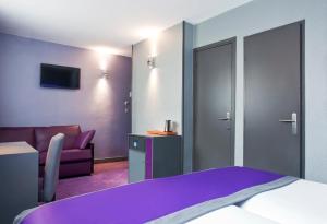 a hotel room with a purple bed and a couch at Hotel des Savoies Lyon Perrache in Lyon