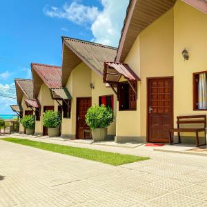 a row of houses with doors and potted plants at Aruanã Chalés in Japaratinga