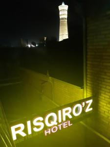 una señal de neón para un hotel con un faro en el fondo en Hotel Rizqiro'z Boutique, en Bukhara