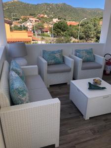 uma varanda com cadeiras de vime e uma mesa de centro em Casa Babila 100 metres from the beach 10 kilometres from Villasimius em Solanas